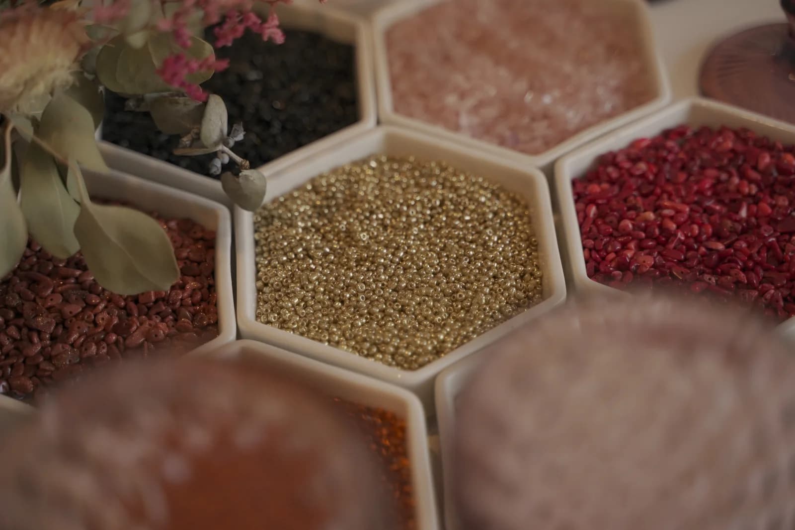 Bandejas hexagonales con cuentas de distintos colores y pequeñas piezas metálicas.