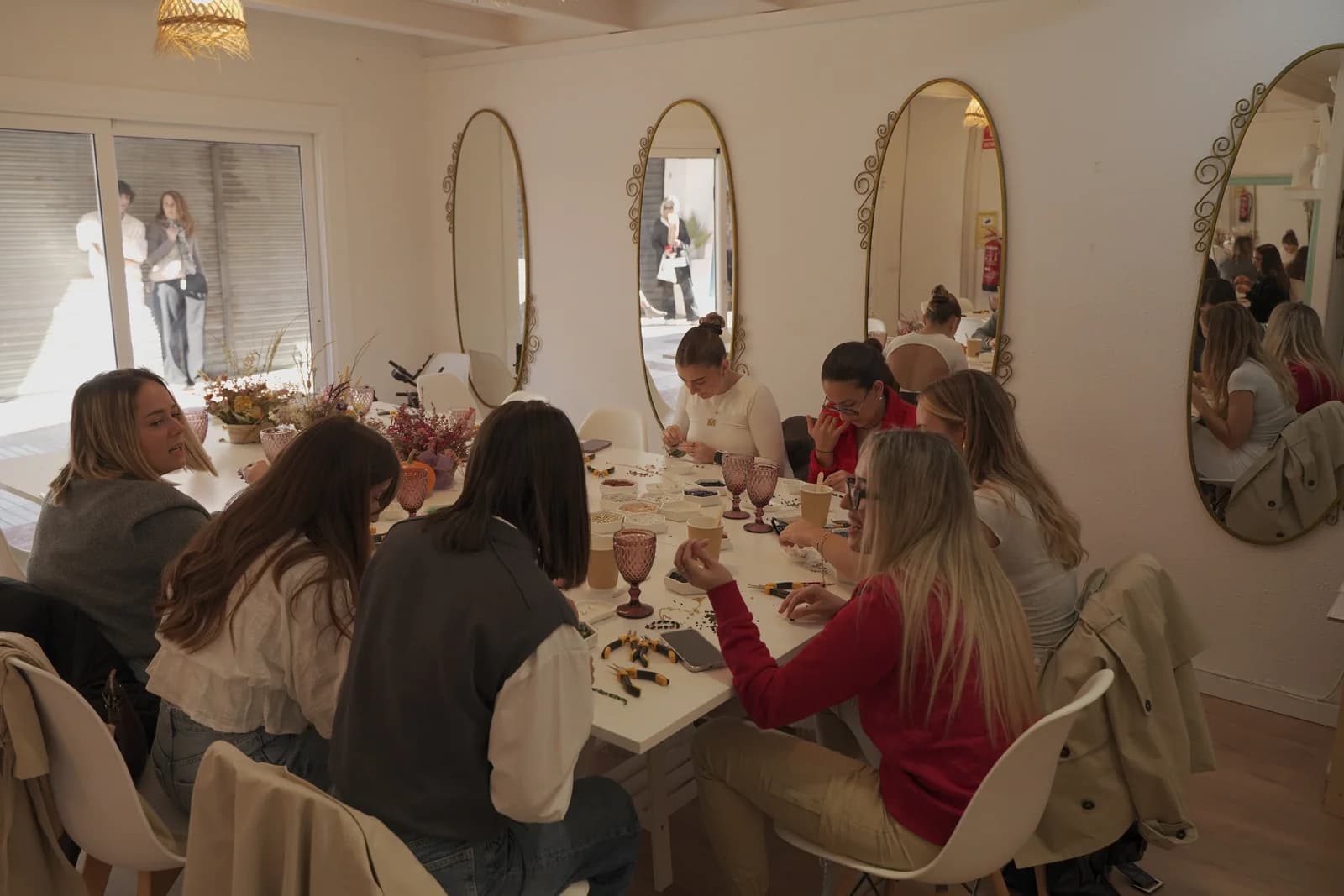 Participantes creando joyas alrededor de una mesa con materiales y herramientas.