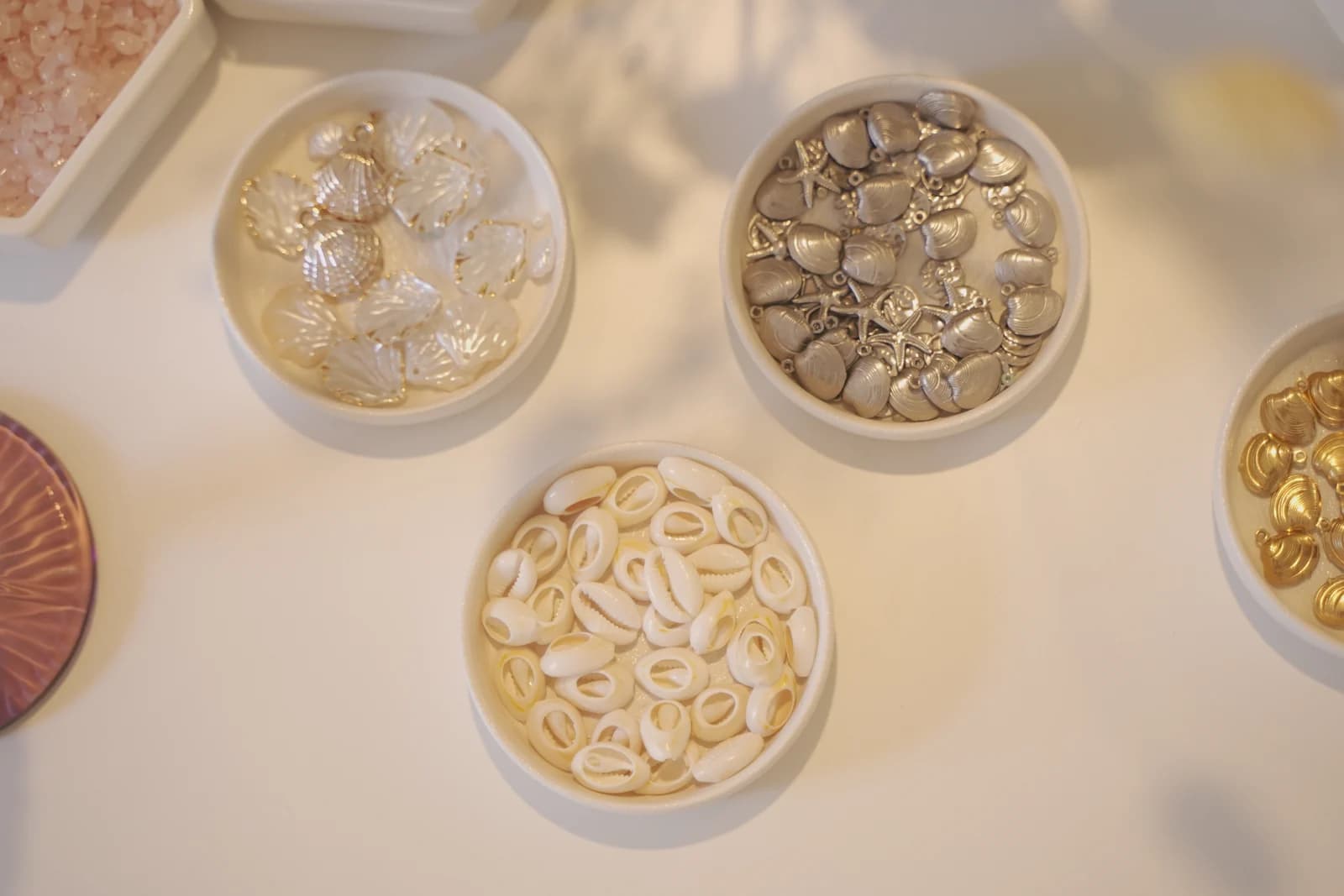 Bandejas con charms de conchas y otros elementos para diseñar joyas