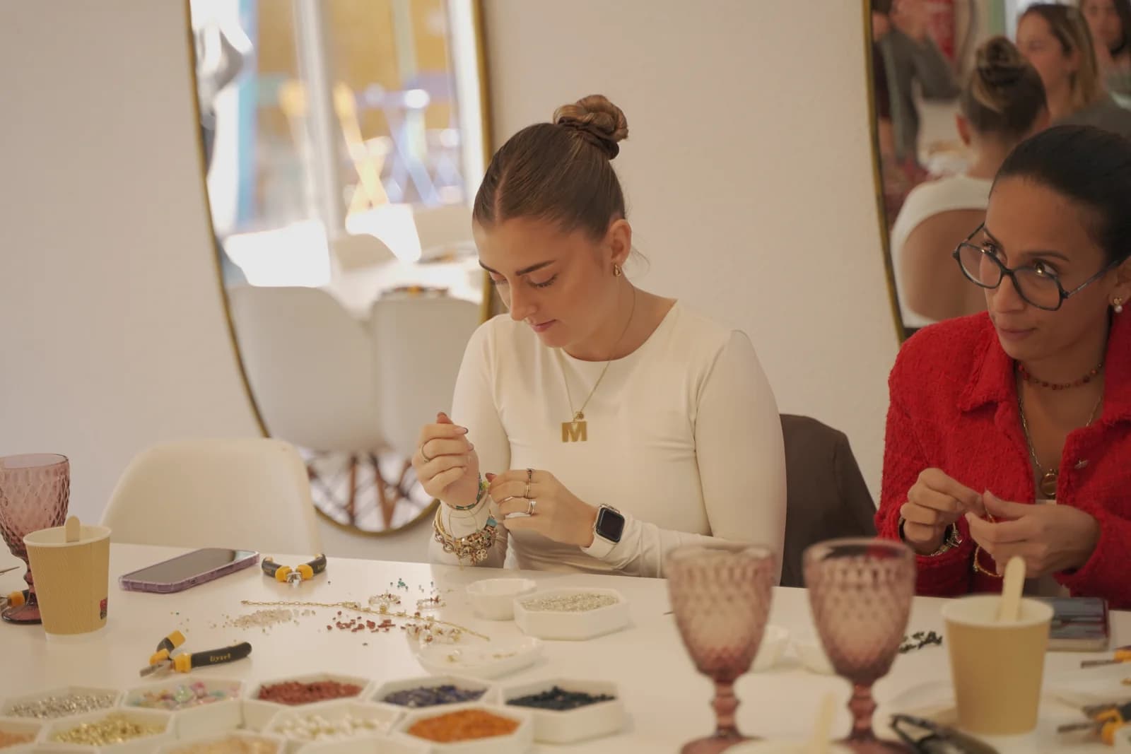 Participantes creando joyas con cuentas y herramientas en la mesa del taller