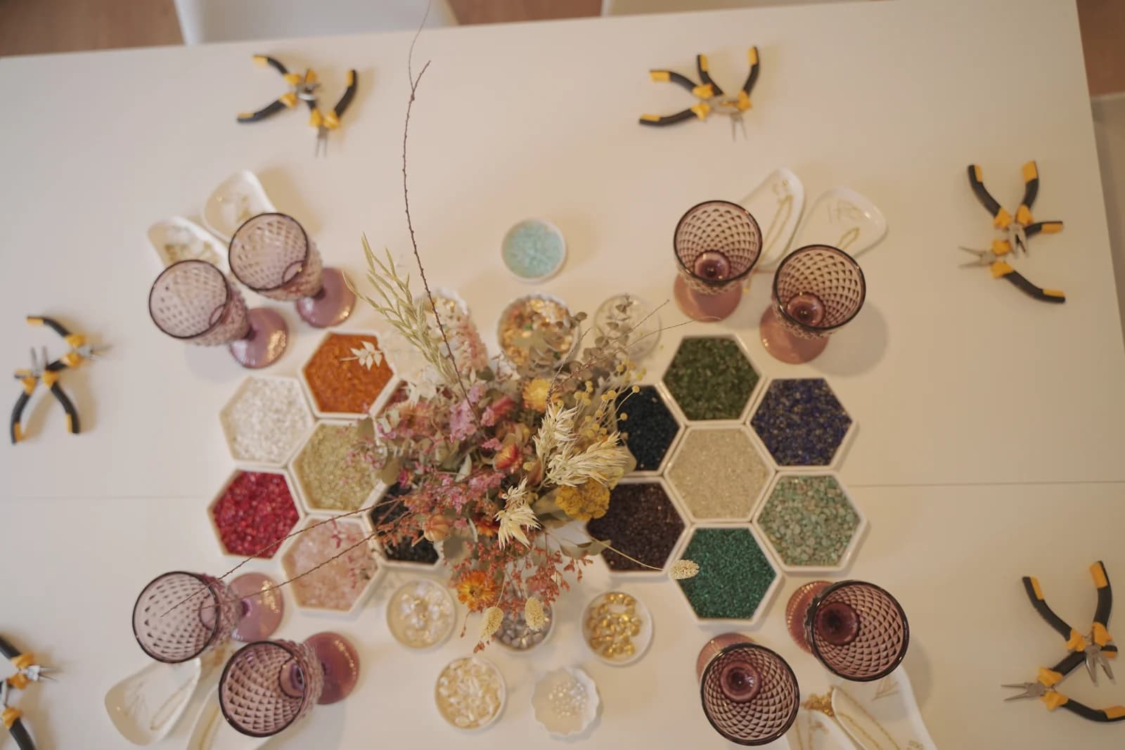 Mesa del taller preparada con herramientas, cuentas de colores y copas